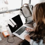 close up photography of woman sitting beside table while using macbook